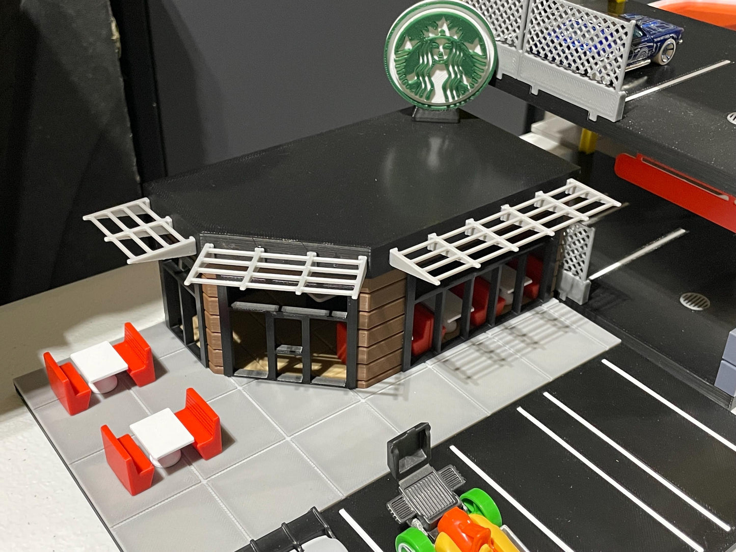 Model of a miniature Starbucks store with green coffee cup on a dark surface
